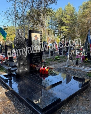 Памятник из чёрного гранита с цветным овальным портретом и цветником