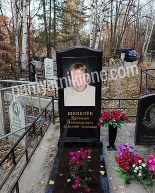 Вертикальный памятник из чёрного гранита с цветным портретом, ограда и цветы