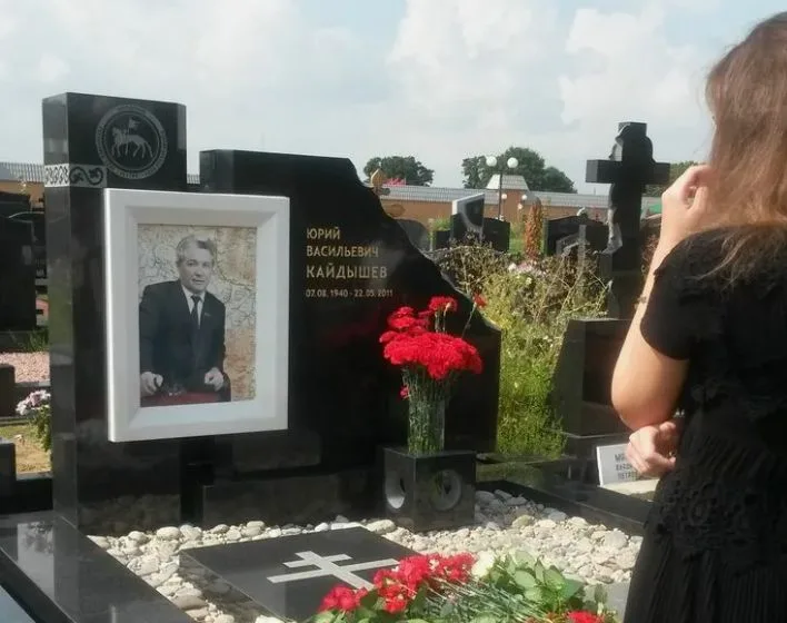 Женщина у памятника с портретом и цветами на могиле